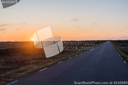 Image of Sunrise by a straight country road in a great plain grassland