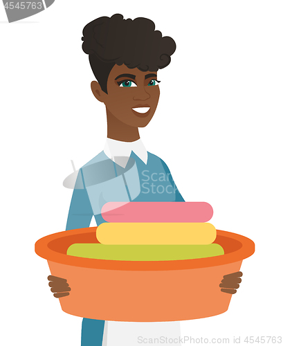 Image of African housewife holding basin with dirty linen.