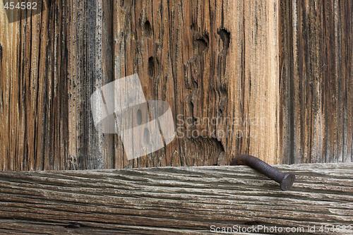 Image of rough, weathered wood and a big, rusty nail