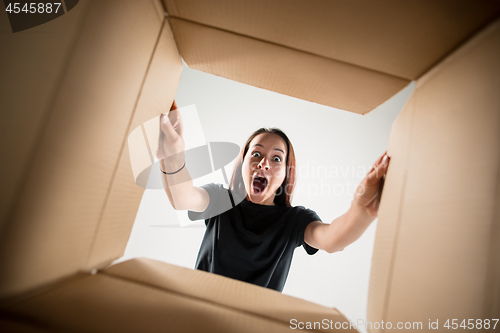 Image of Woman unpacking and opening carton box and looking inside