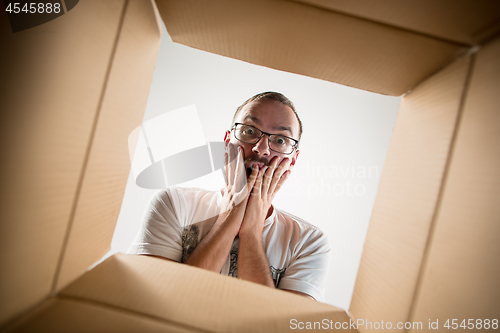 Image of Man unpacking and opening carton box and looking inside