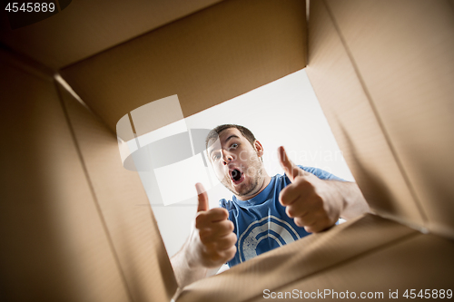 Image of Man unpacking and opening carton box and looking inside