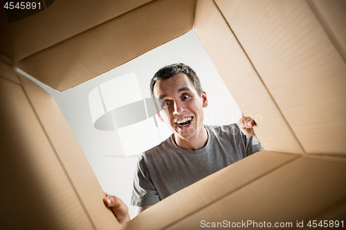 Image of Man unpacking and opening carton box and looking inside