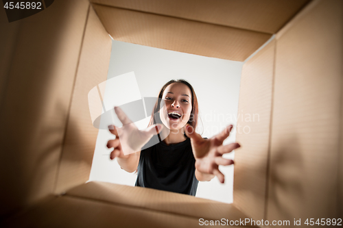 Image of Woman unpacking and opening carton box and looking inside