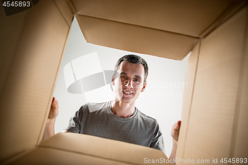 Image of Man unpacking and opening carton box and looking inside