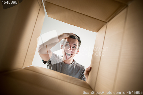 Image of Man unpacking and opening carton box and looking inside