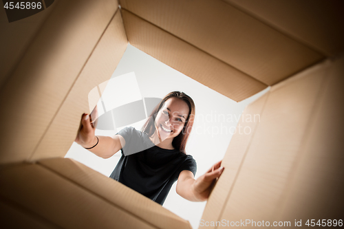 Image of Woman unpacking and opening carton box and looking inside