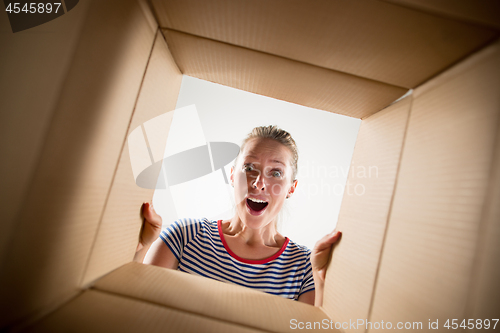 Image of Woman unpacking and opening carton box and looking inside