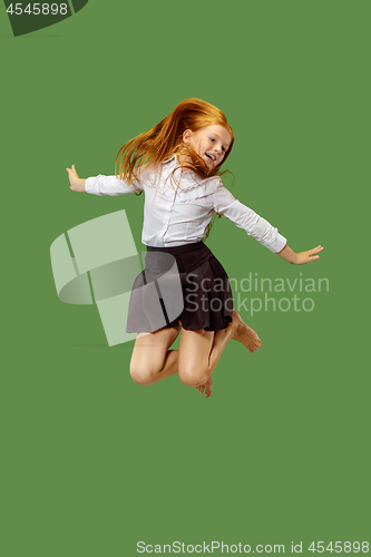 Image of Young happy caucasian teen girl jumping in the air , isolated on green background