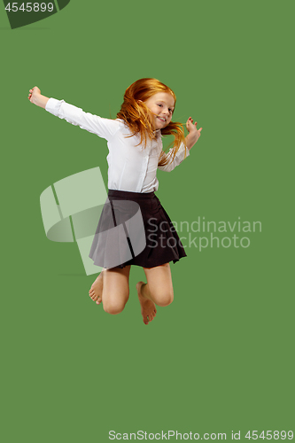 Image of Young happy caucasian teen girl jumping in the air , isolated on green background