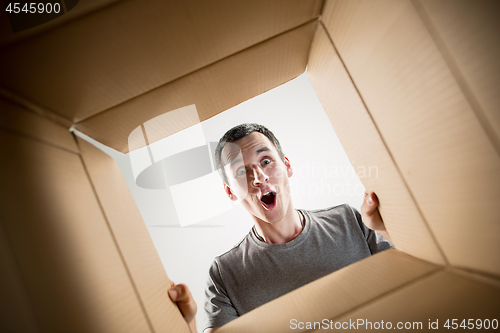 Image of Man unpacking and opening carton box and looking inside