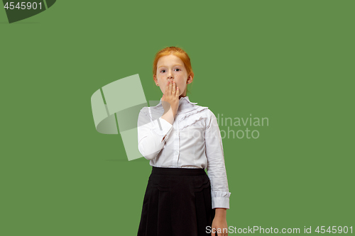 Image of The young teen girl whispering a secret behind her hand over green background