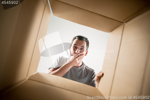 Image of Man unpacking and opening carton box and looking inside