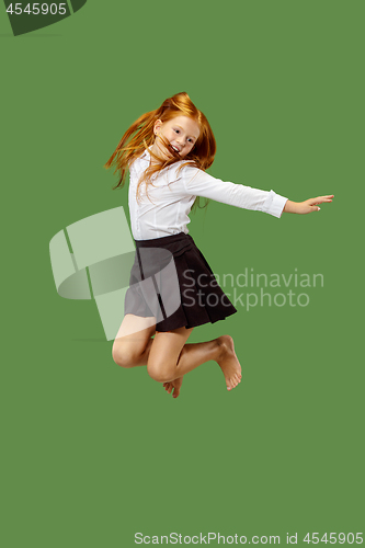 Image of Young happy caucasian teen girl jumping in the air , isolated on green background