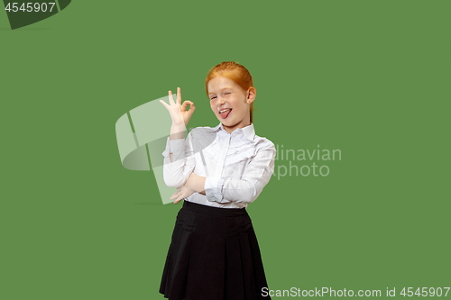 Image of The happy teen girl standing and smiling against p green background.