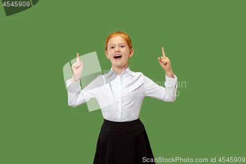 Image of The happy teen girl standing and smiling against green background.