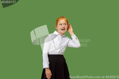 Image of The young teen girl whispering a secret behind her hand over green background