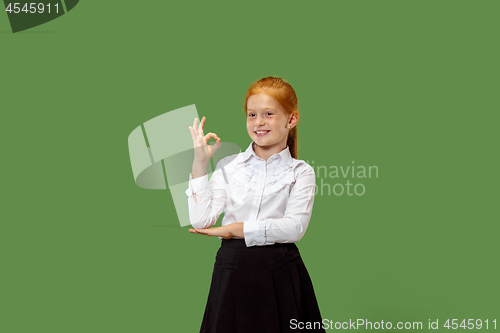 Image of The happy teen girl standing and smiling against p green background.