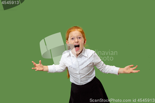 Image of The young emotional angry teen girl screaming on green studio background