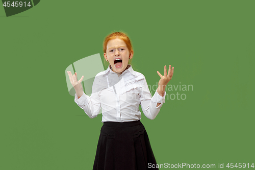 Image of The young emotional angry teen girl screaming on green studio background