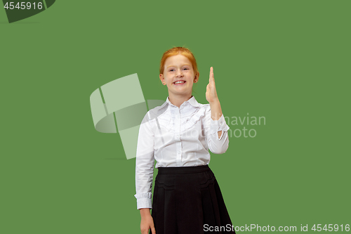 Image of The happy teen girl standing and smiling against green background.