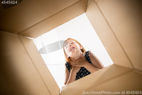 Image of The girl unpacking and opening carton box and looking inside