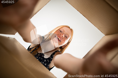 Image of The girl unpacking and opening carton box and looking inside