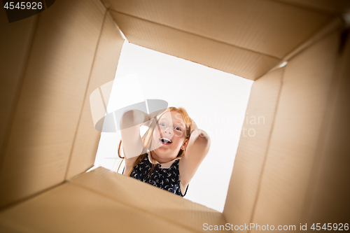 Image of The girl unpacking and opening carton box and looking inside