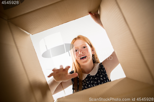 Image of The girl unpacking and opening carton box and looking inside