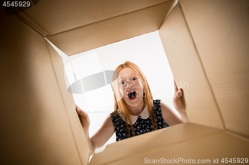 Image of The girl unpacking and opening carton box and looking inside