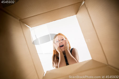 Image of The girl unpacking and opening carton box and looking inside