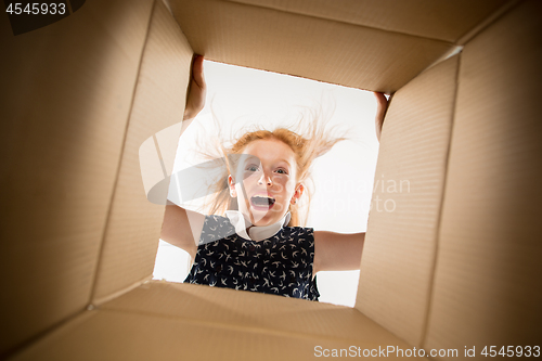 Image of The girl unpacking and opening carton box and looking inside