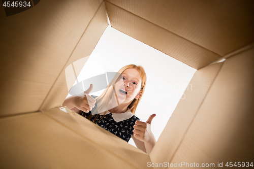 Image of The girl unpacking and opening carton box and looking inside