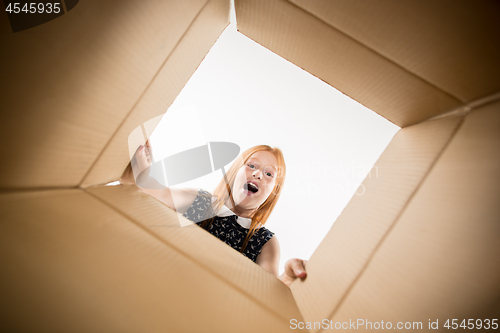 Image of The girl unpacking and opening carton box and looking inside