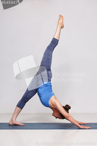 Image of Woman doing Hatha yoga Eka pada adhomukha svanasana