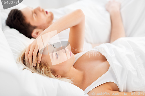 Image of unhappy woman in bed with snoring sleeping man