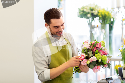 Image of smiling florist man making bunch at flower shop