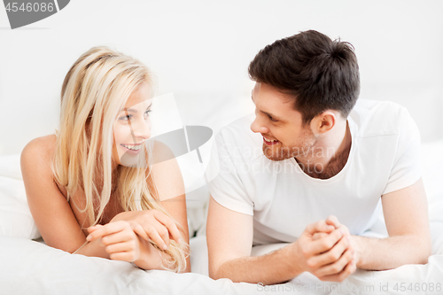 Image of happy couple lying in bed at home