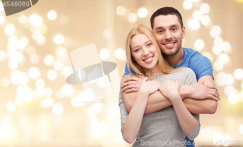 Image of smiling couple hugging over festive lights