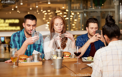 Image of friends with smartphones at restaurant