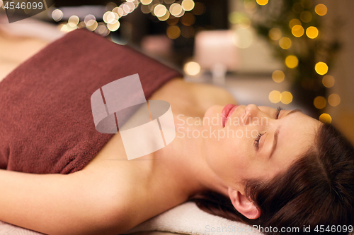 Image of happy young woman lying at spa or massage parlor