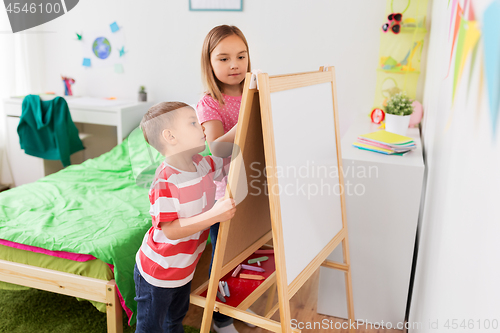 Image of happy kids drawing on easel or flip board at home