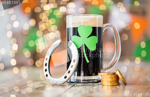 Image of shamrock on glass of beer, horseshoe and coins