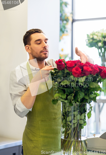 Image of florist or seller setting red roses at flower shop