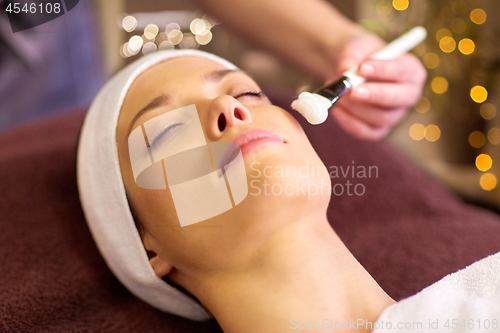 Image of beautician applying facial mask to woman at spa