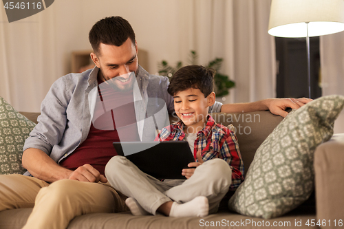 Image of father and son with tablet pc playing at home