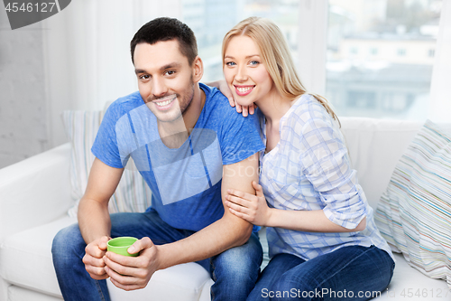 Image of happy couple sitting on sofa and hugging at home