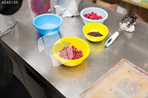 Image of berries in bowls at confectionery shop kitchen