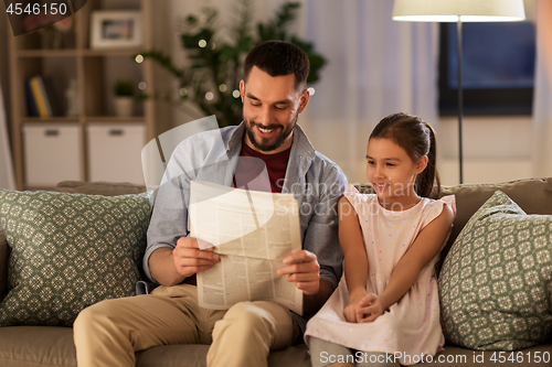 Image of father reading newspaper to daughter at home