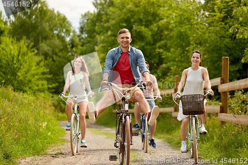 Image of happy friends riding fixed gear bicycles in summer